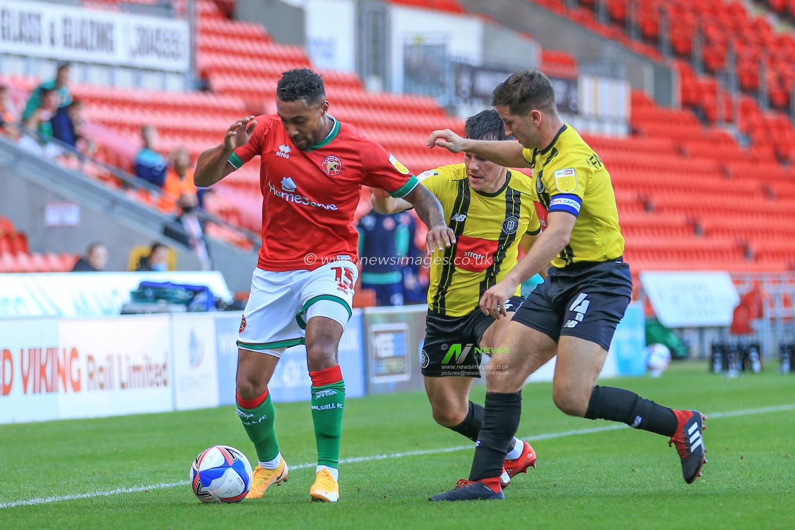 Wes McDonald (15) of Walsall and Josh Falkingham (4) of Harrogate Town contest for the ball