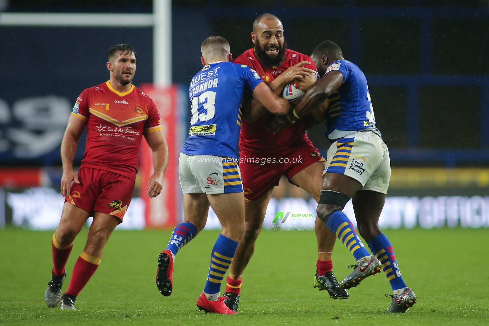 Sam Kasiano(28) of Catalan Dragons tackled by Jarrod Oâ€™Connor and Muizz Musapha of Leeds Rhinos.