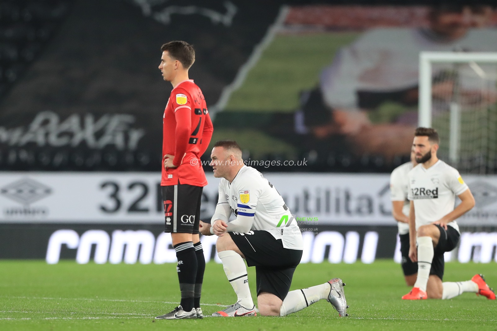 Wayne Rooney (32) of Derby County takes the knee as Tom Carroll (22) of Queens Park Rangers choses not to