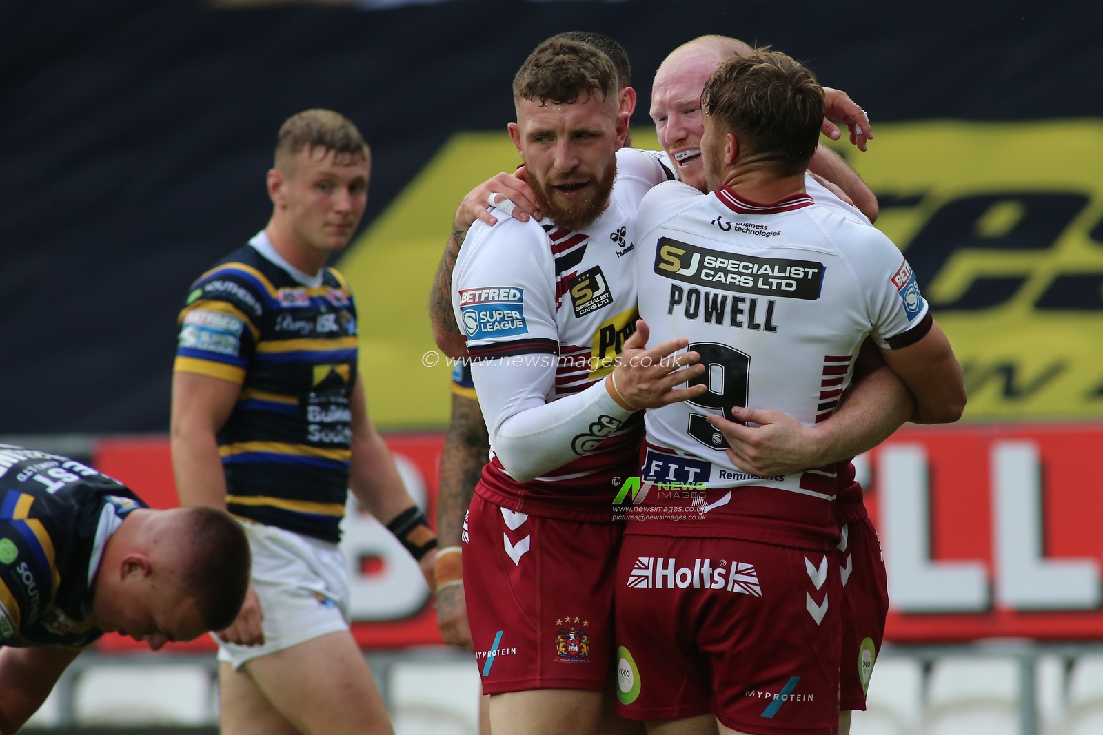 Liam Marshall (C) of Wigan Warriors celebrates scoring his try with team mates Jacksons Hastings (31) and Sam Powell (9).