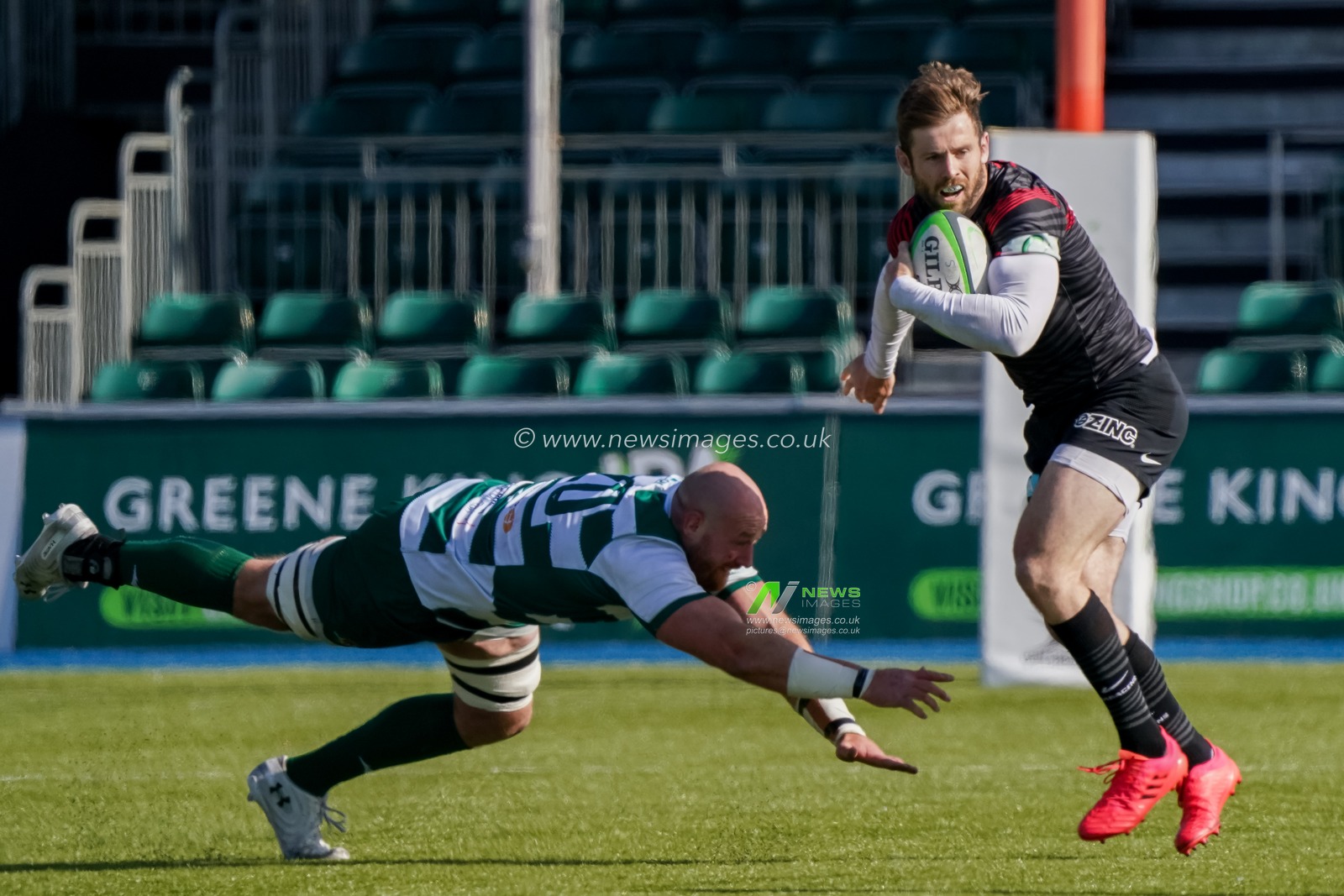 Elliot Daly #13 of Saracens avoids  Guy Thompson #20 of Ealing Trailfinders