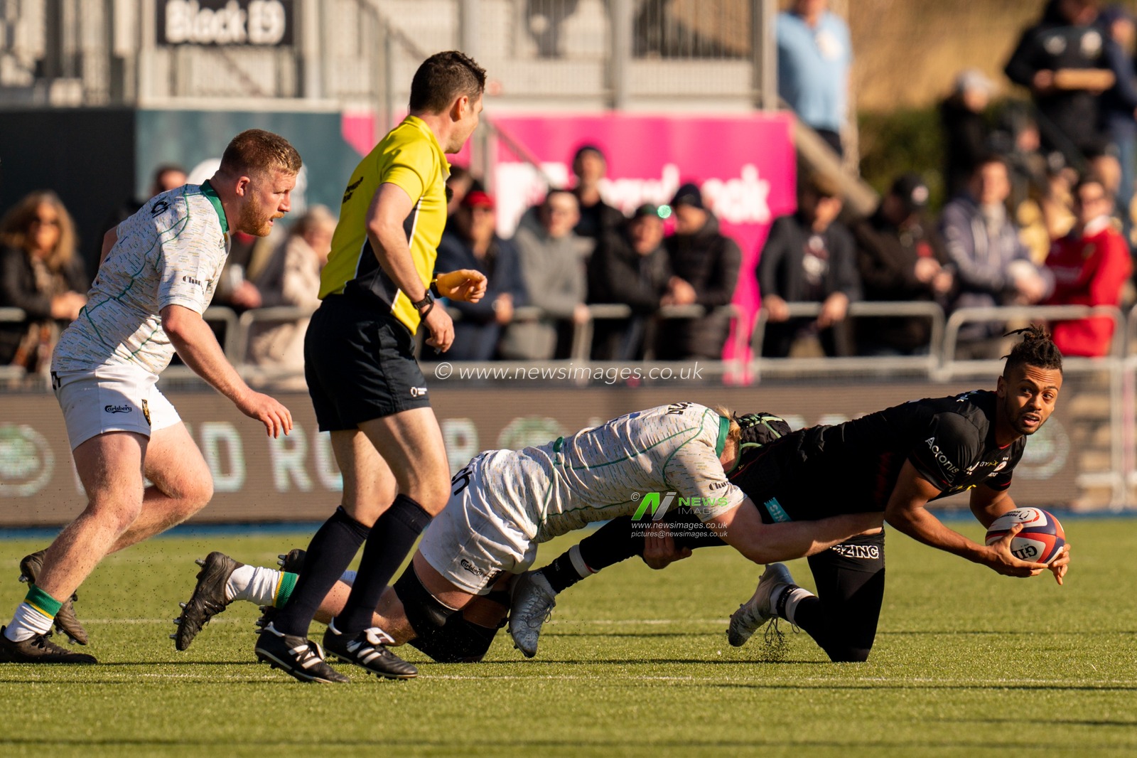 Elliot Obatoyinbo #15 of Saracens is tackled by  Luke Frost #5 of Northampton Saints