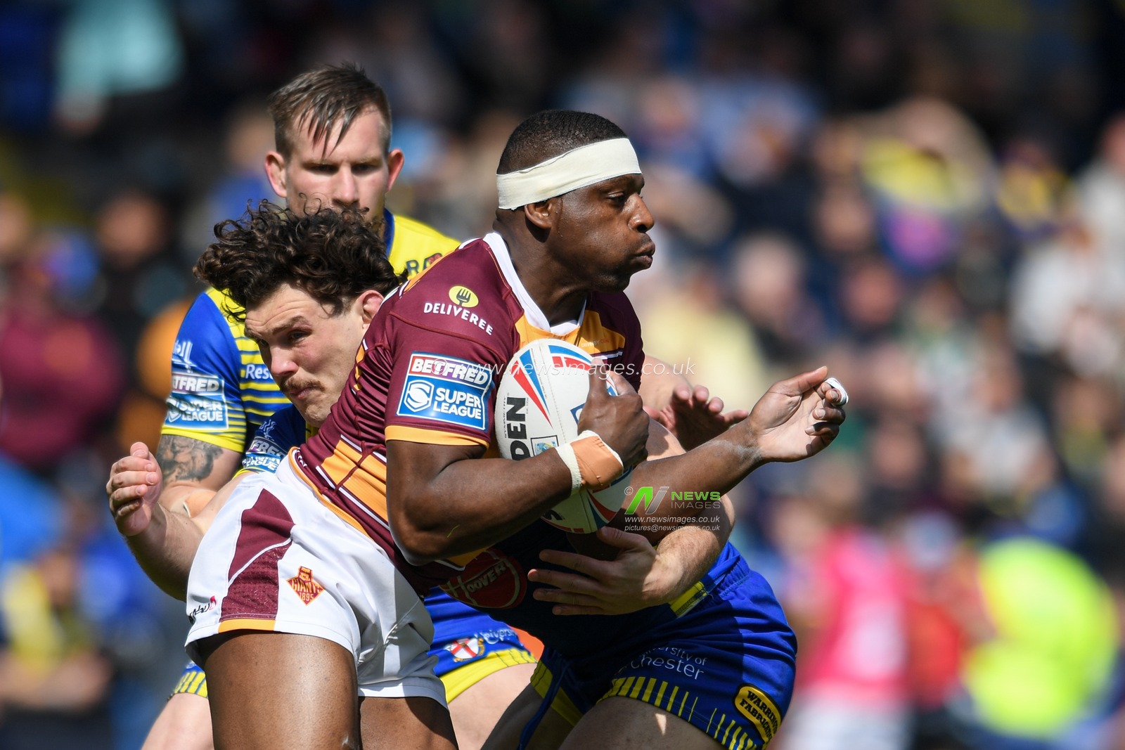 Jermaine McGillvary #2 of Huddersfield Giants is tackled by Rob Mulhern #19 of Warrington Wolves