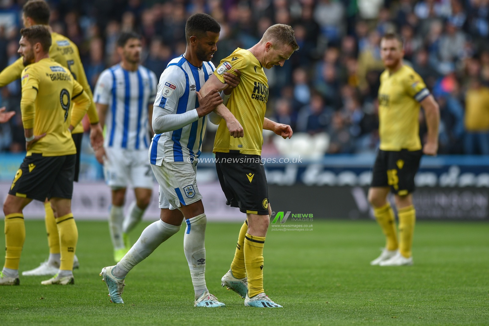 28th September 2019, John Smith's Stadium, Huddersfield, England; Sky Bet Championship, Huddersfield Town v Millwall :Fraizer Cambell (22) of Huddersfield Town assists Shane Ferguson (11) of Millwall off the field after the Millwall player feigns injury getting sent off.

Credit: Dean Williams/News Images