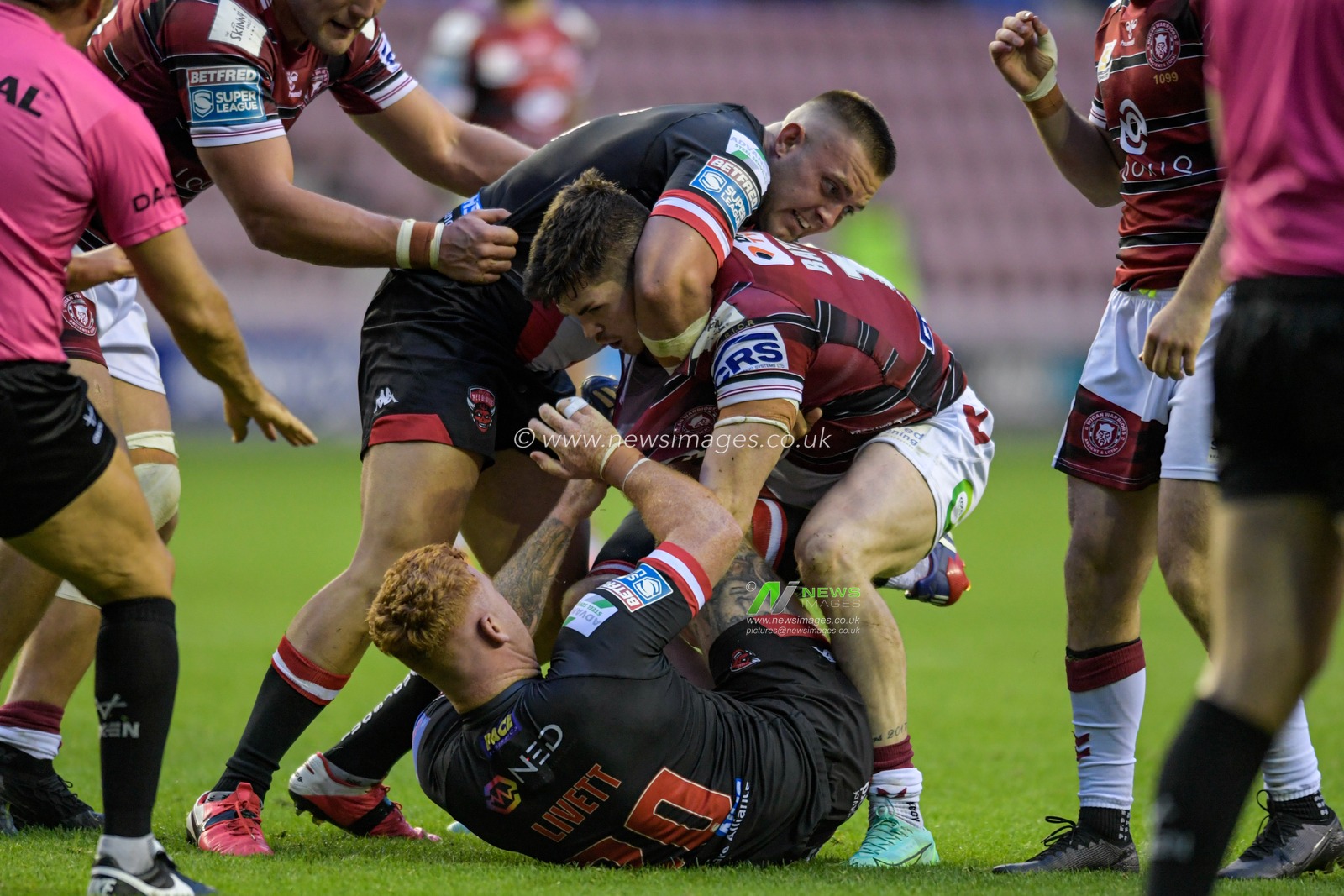 John Bateman (13) of Wigan Warriors and Harvey Livett (20) of Salford Red Devils clash on the pitch