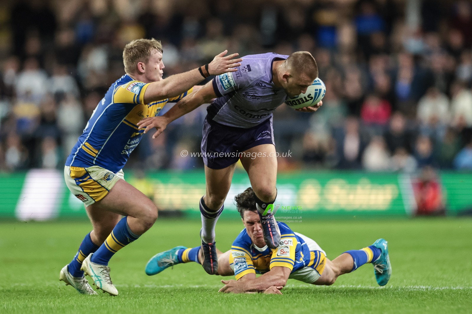 Mikey Lewis of Hull KR breaks with the ball as Brodie Croft of Leeds Rhinos fails to stop him but James McDonnell of Leeds Rhinos makes the tackle during the Betfred Super League round 23 match Leeds Rhinos vs Hull KR at Headingley Stadium, Leeds, United Kingdom, 21st August 2025

(Photo by Mark Cosgrove/News Images)
