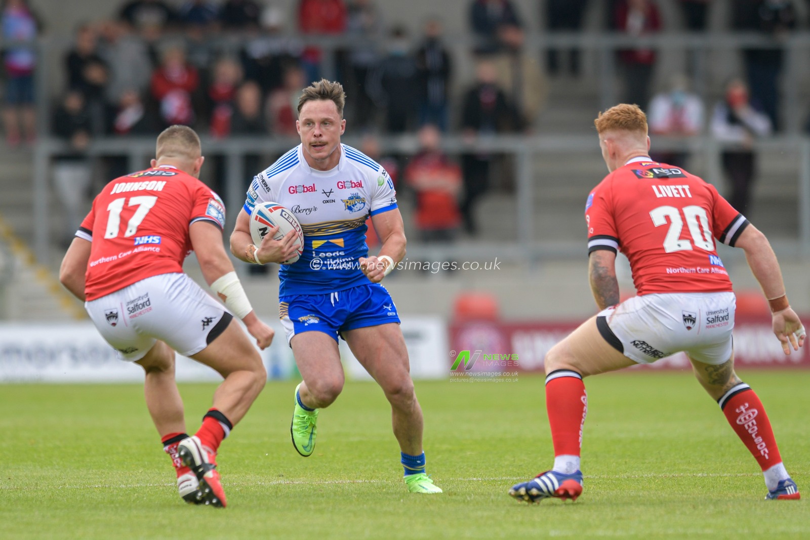 James Donaldson (25) of Leeds Rhinos looks for a way past Josh Johnson (17) of Salford Red Devils and Harvey Livett (20) of Salford Red Devils