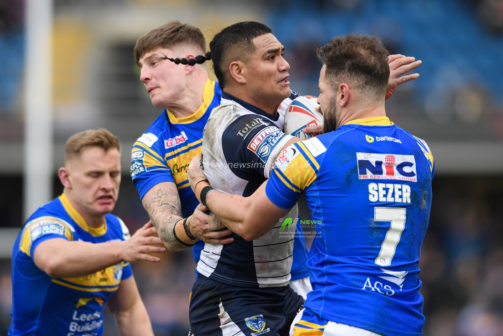 Peter Mataâ€™utia #3 of Warrington Wolves is tackled by Liam Sutcliffe #4 and Aidan Sezer #7 of Leeds Rhinos