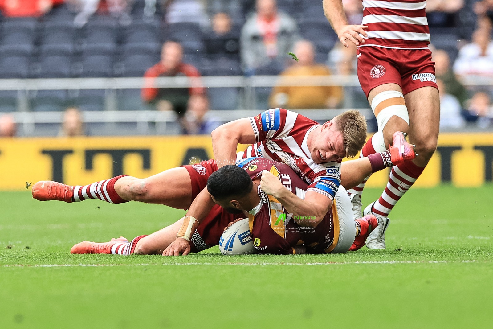 Ricky Leutele #4 of Huddersfield Giants is tackled by Morgan Smithies #14 of Wigan Warriors