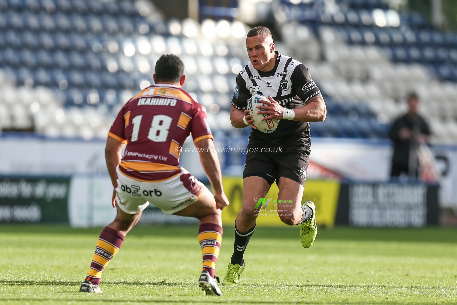 Kane Evans #16 of Hull FC runs at Sebastine Ikahihifo #18 of Huddersfield Giants