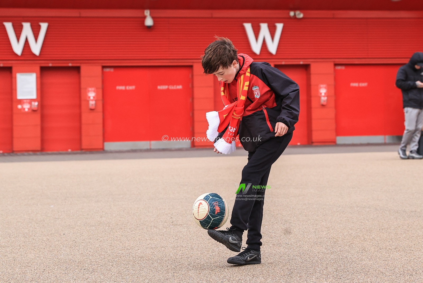 A young Liverpool fan doing kick-ups outside Anfield