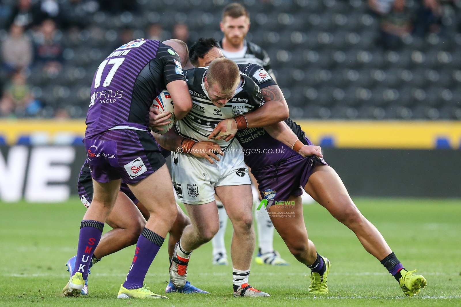 Brad Fash (19) of Hull FC is tackled by the Leeds defence