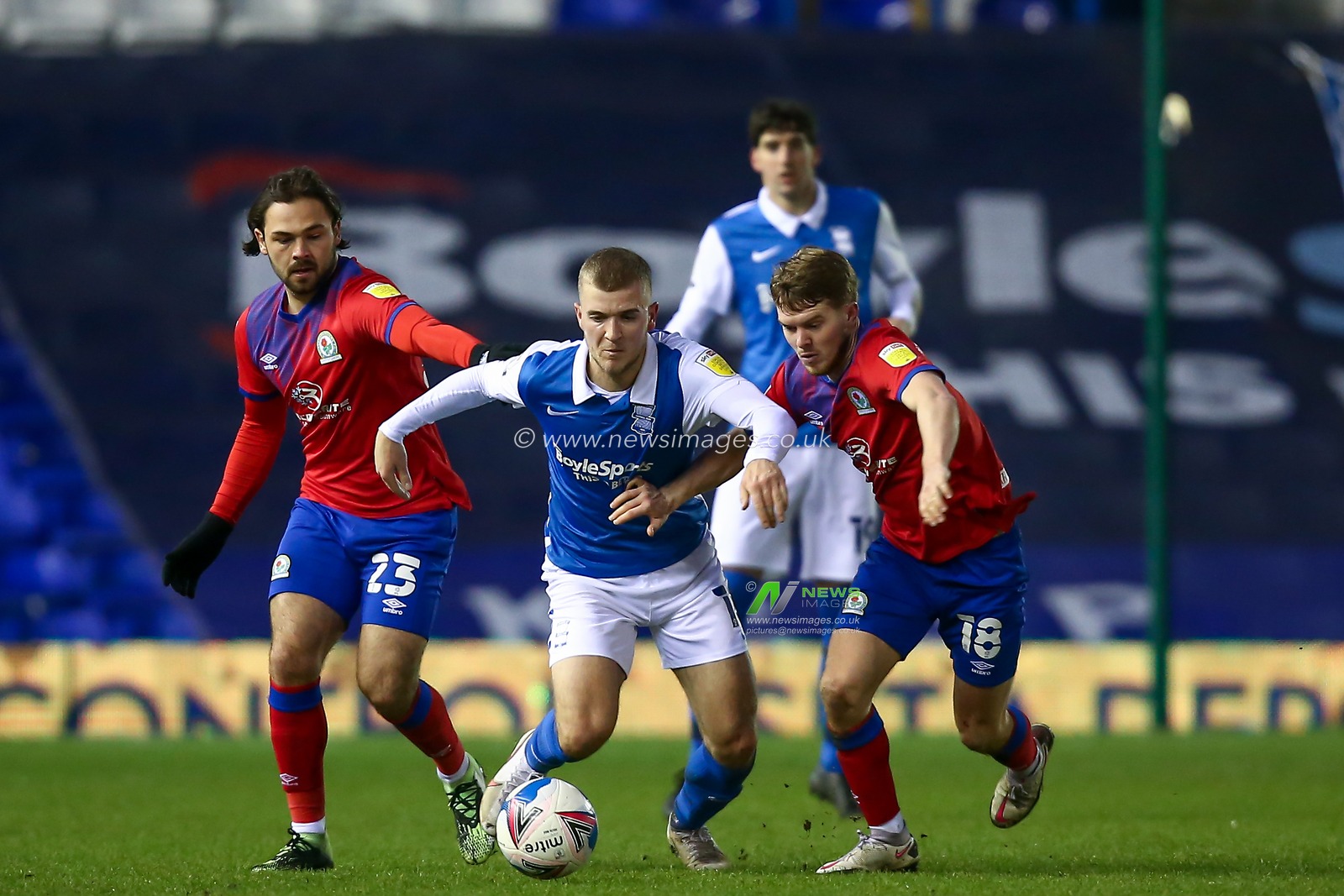 Riley McGree #18 of Birmingham City dribbles the ball away from Bradley Dack #23 and Jacob Davenport #18 of Blackburn Rovers