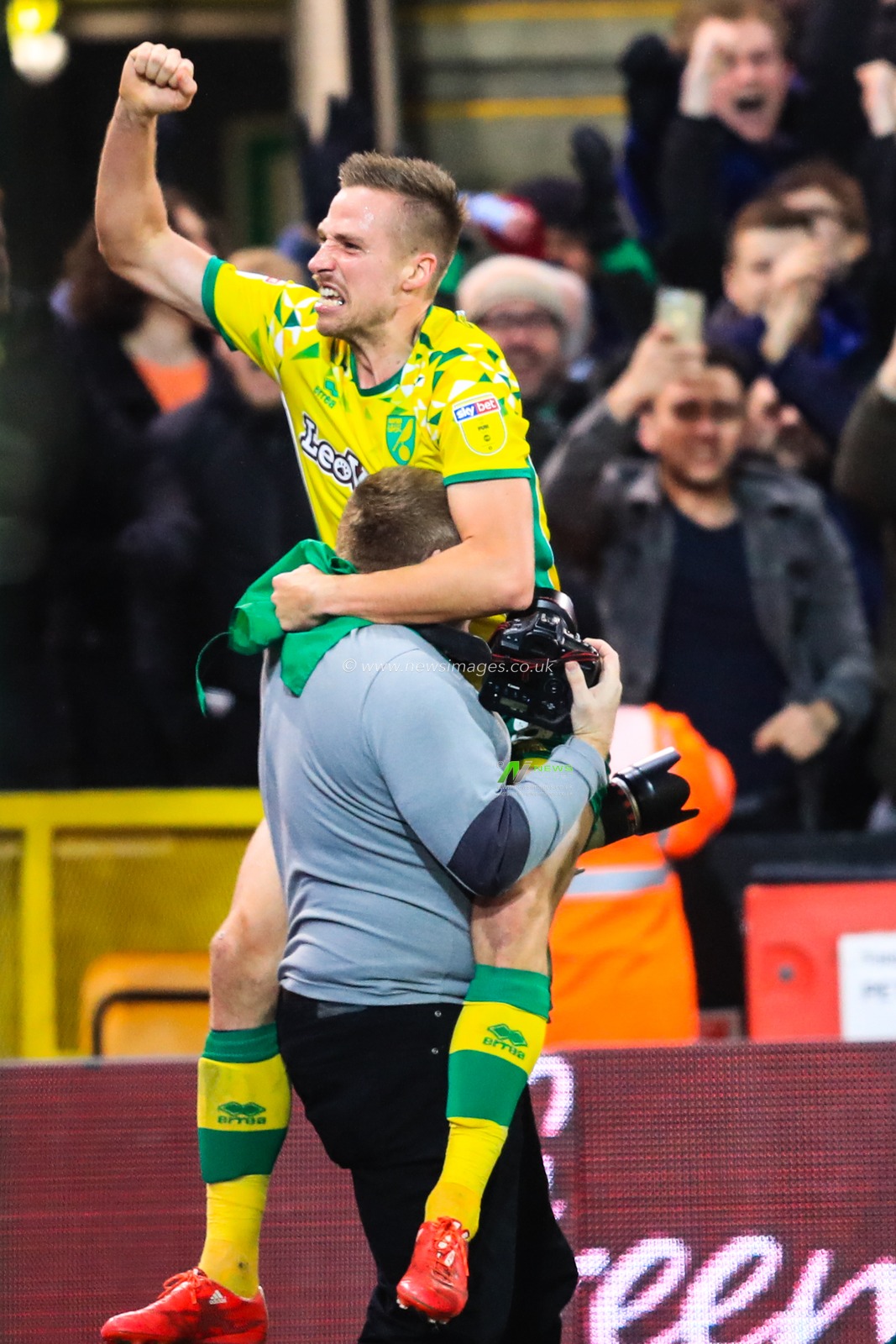 26th December 2018, Carrow Road, Norfolk, England; Sky Bet Championship, Norwich City vs Nottingham Forest ;  A photographer joins in the celebrations with Marco Stiepermann (18) of Norwich City as they level the score at 3-3, following a dramatic comeback goal from Onel Hernandez (25).

Credit: Georgie Kerr/News Images

English Football League images are subject to DataCo Licence