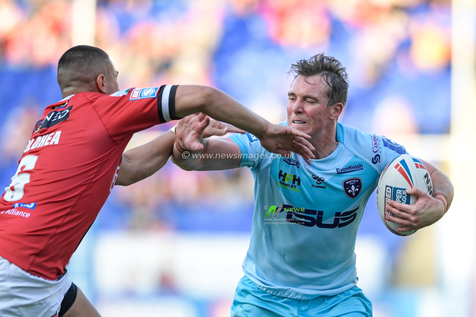 Matty Ashurst (11) of Wakefield Trinity looks to hold off the tackle attempt by Tui Lolohea (6) of Salford Red Devils