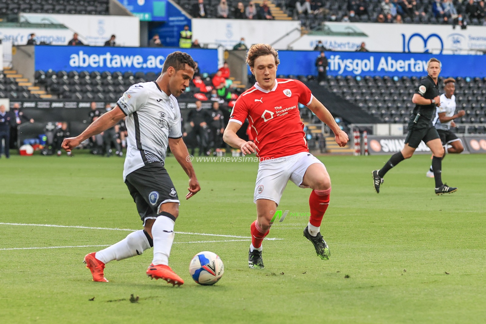 Wayne Routledge #15 of Swansea City clears the ball under pressure from Callum Styles #4 of Barnsley
