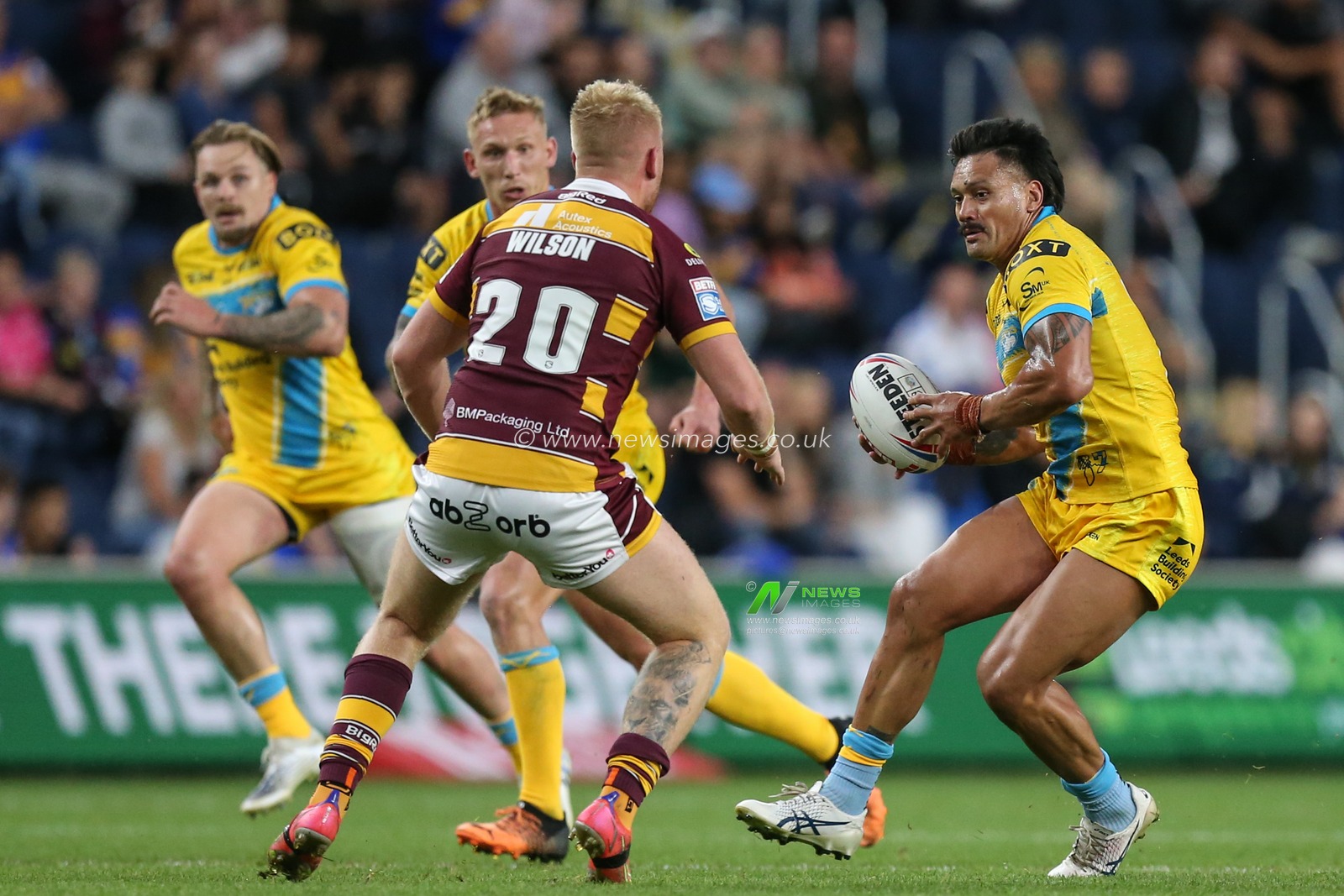 Zane Tetevano #13 of Leeds Rhinos runs at Oliver Wilson #20 of Huddersfield Giants