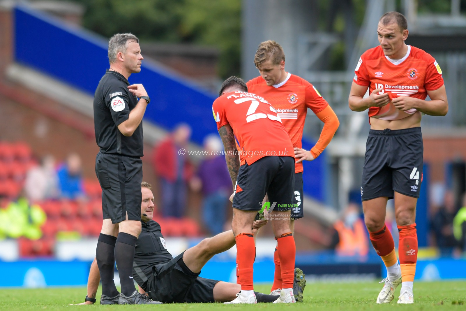 Henri Lansbury #23 of Luton Town helps referee Oliver Langford with his injury