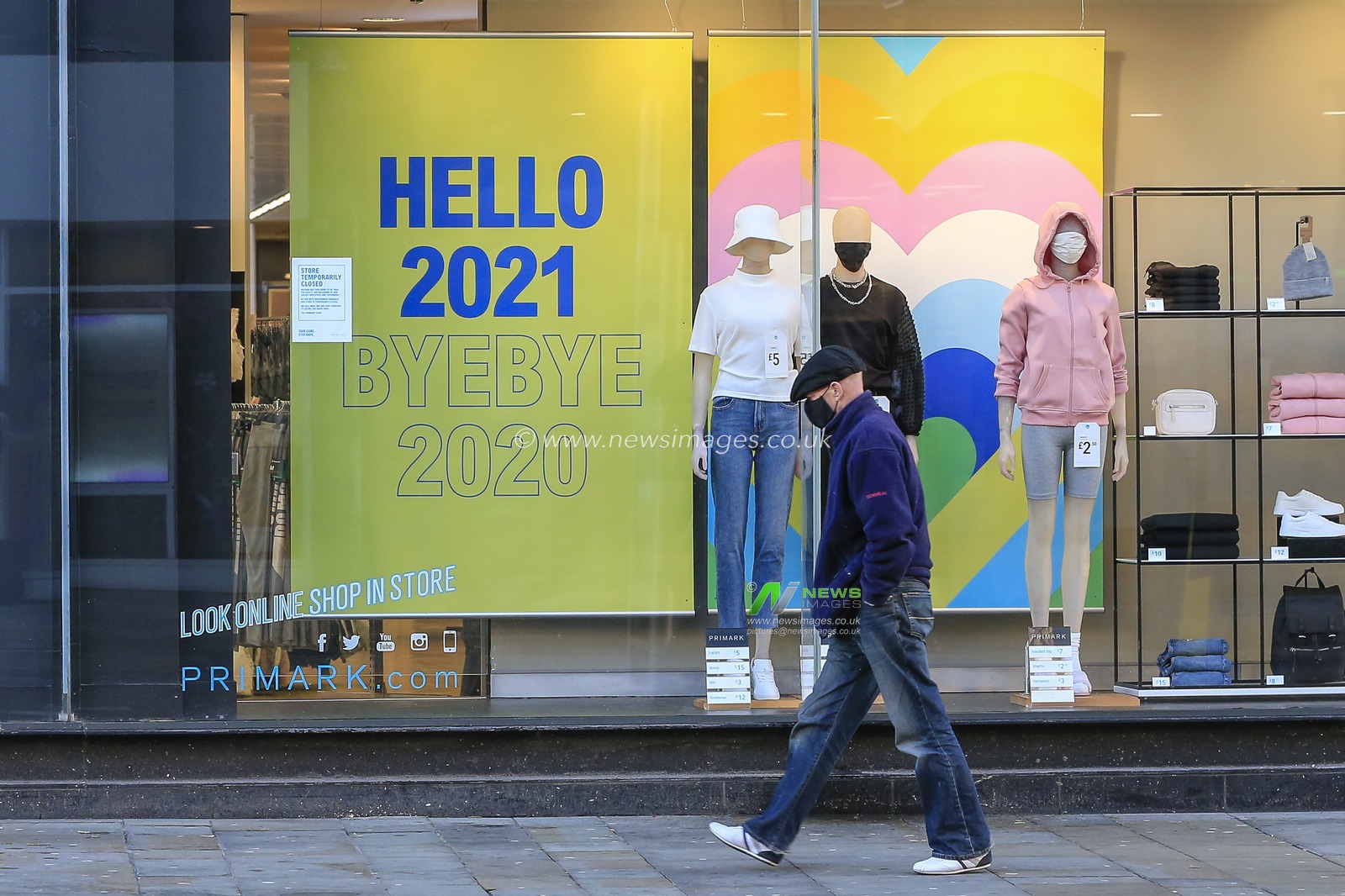 Man walks past Primark on Northumberland Street in Newcastle upon Tyne not noticing the sign which says Hello 20201, Bye Bye 2020.