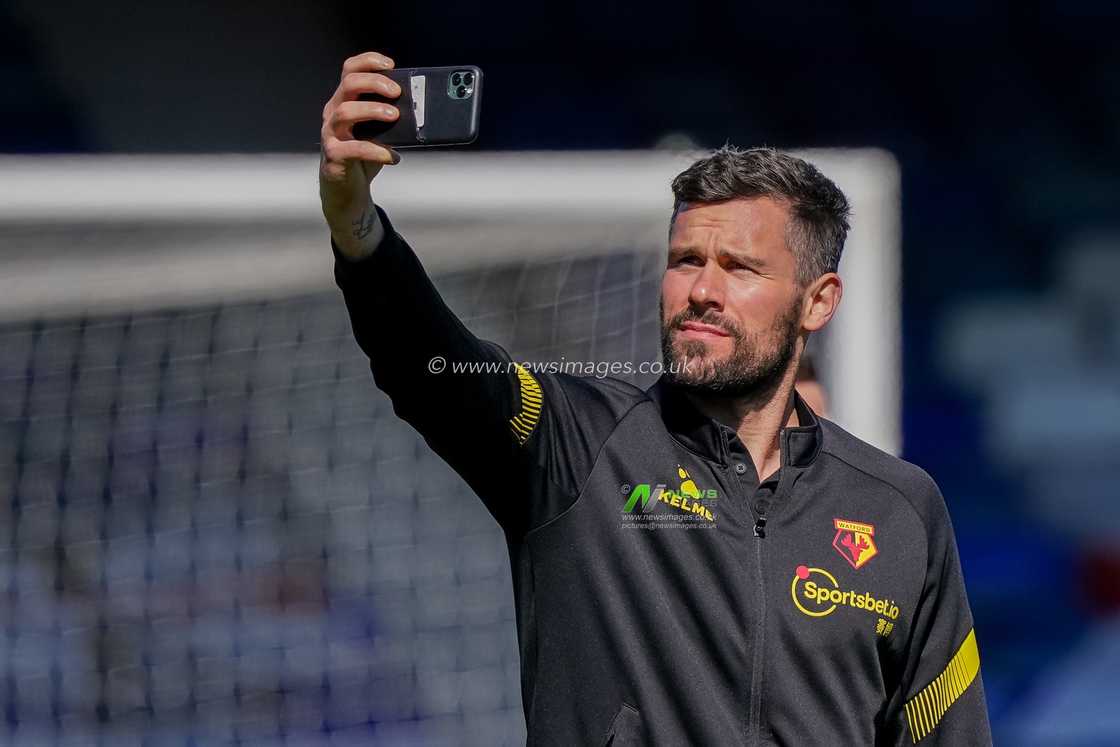 Ben Foster #1 of Watford on his phone pitch inspection