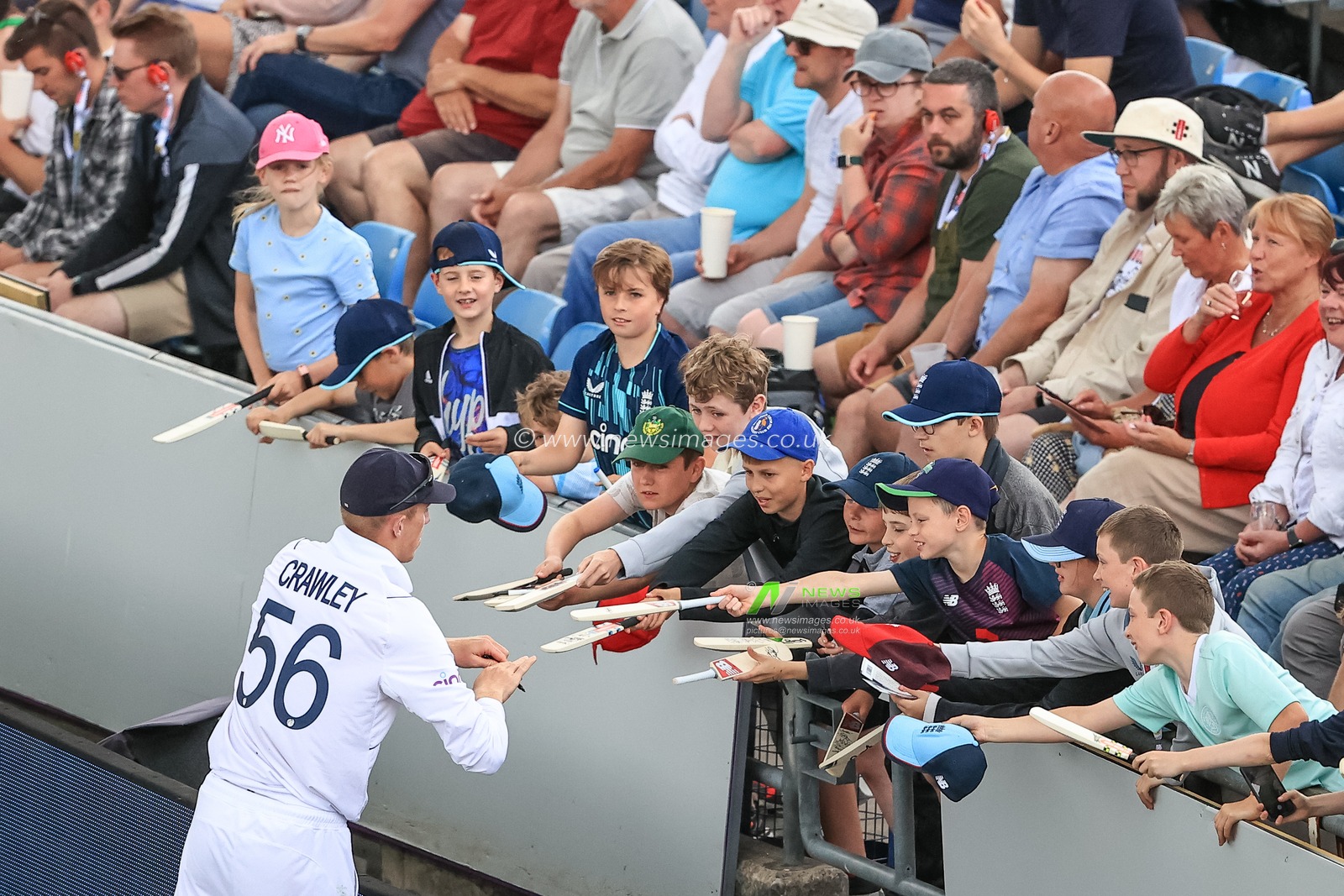 A row of young fans line up to get their bats signed by Zak Crawley of England