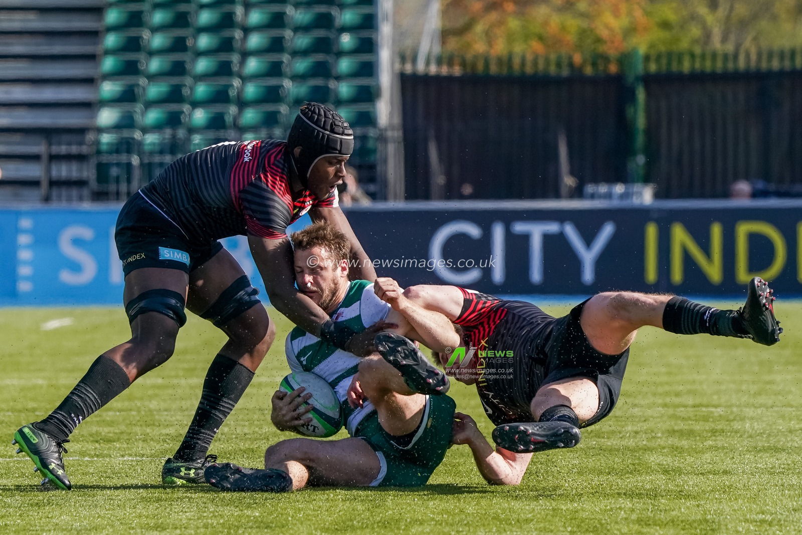 Pat Howard #12 of Ealing Trailfinders is tackled by  Maro Itoje #4 of Saracens and  Owen Farrell #10 of Saracens
