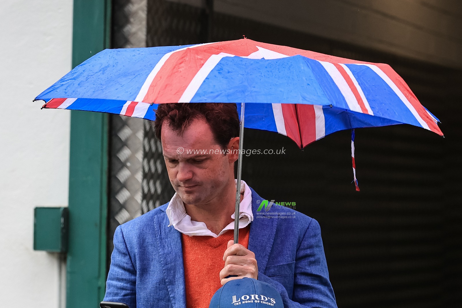 One punter under a Union Jack umbrella as rain pours