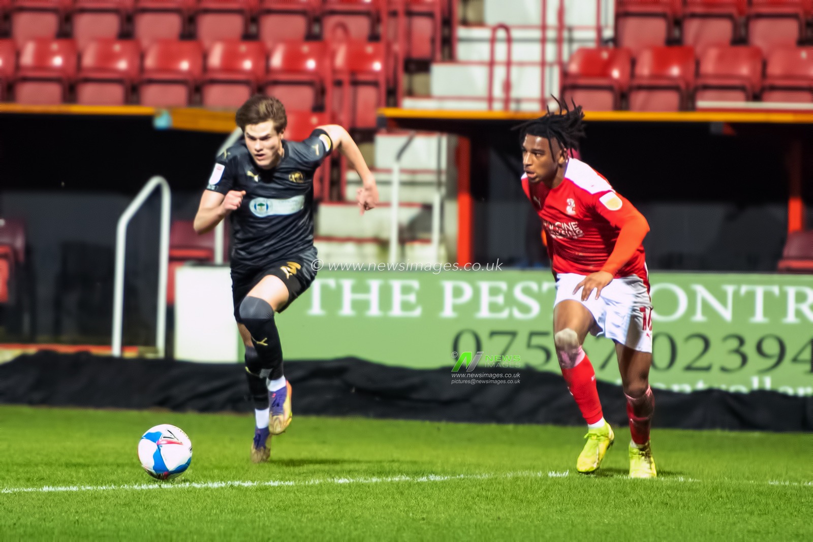 Tom Pearce #3 of Wigan Athletic cuts inside Akinwale Odimayo #16 of Swindon Town to line up a shot at goal