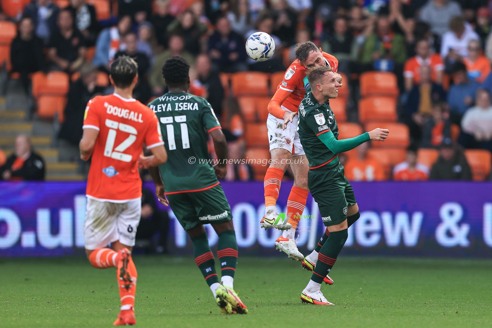 Richard Keogh #26 of Blackpool heads clear as Cauley Woodrow #9 of Barnsley pressures