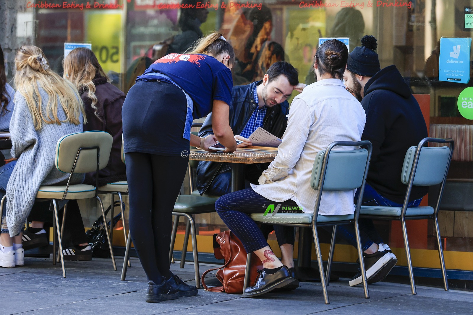 A member of staff takes a breakfast order from a group of people at Turtle Bay, Newgate Street, Newcastle upon Tyne, as restaurants reopen for outside service after national lockdown restrictions were eased