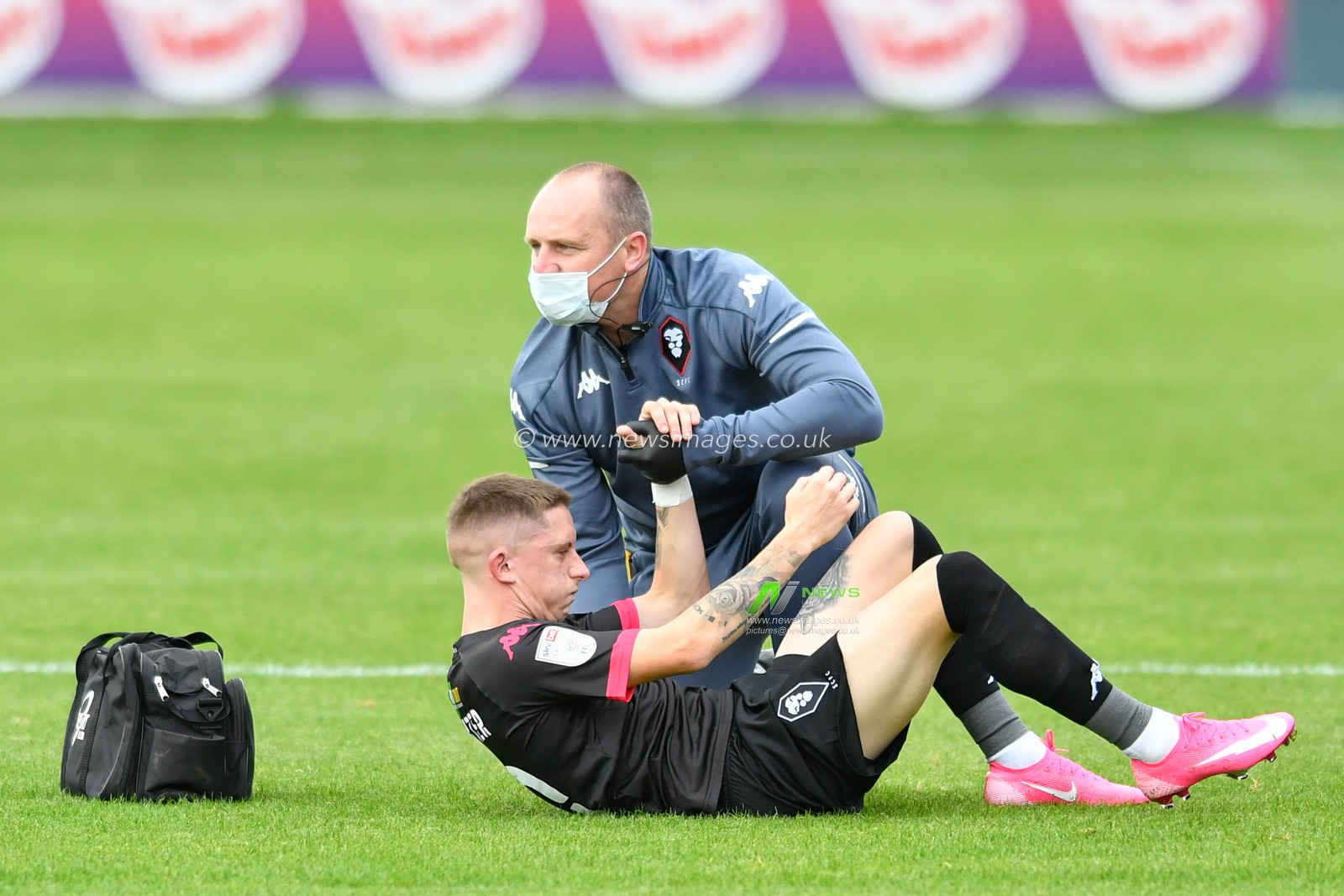 Ash Hunter (10) of Salford City receives treatment on the pitch after an injury