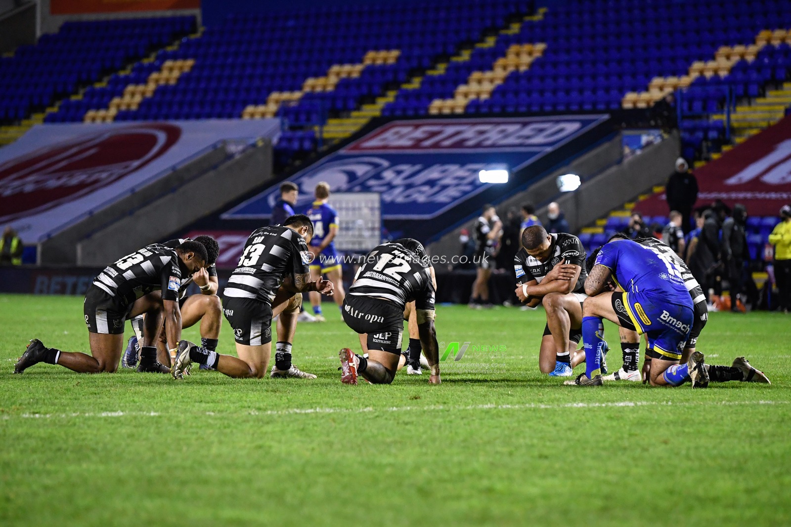 Players from both teams share a group prayer at the end of the game