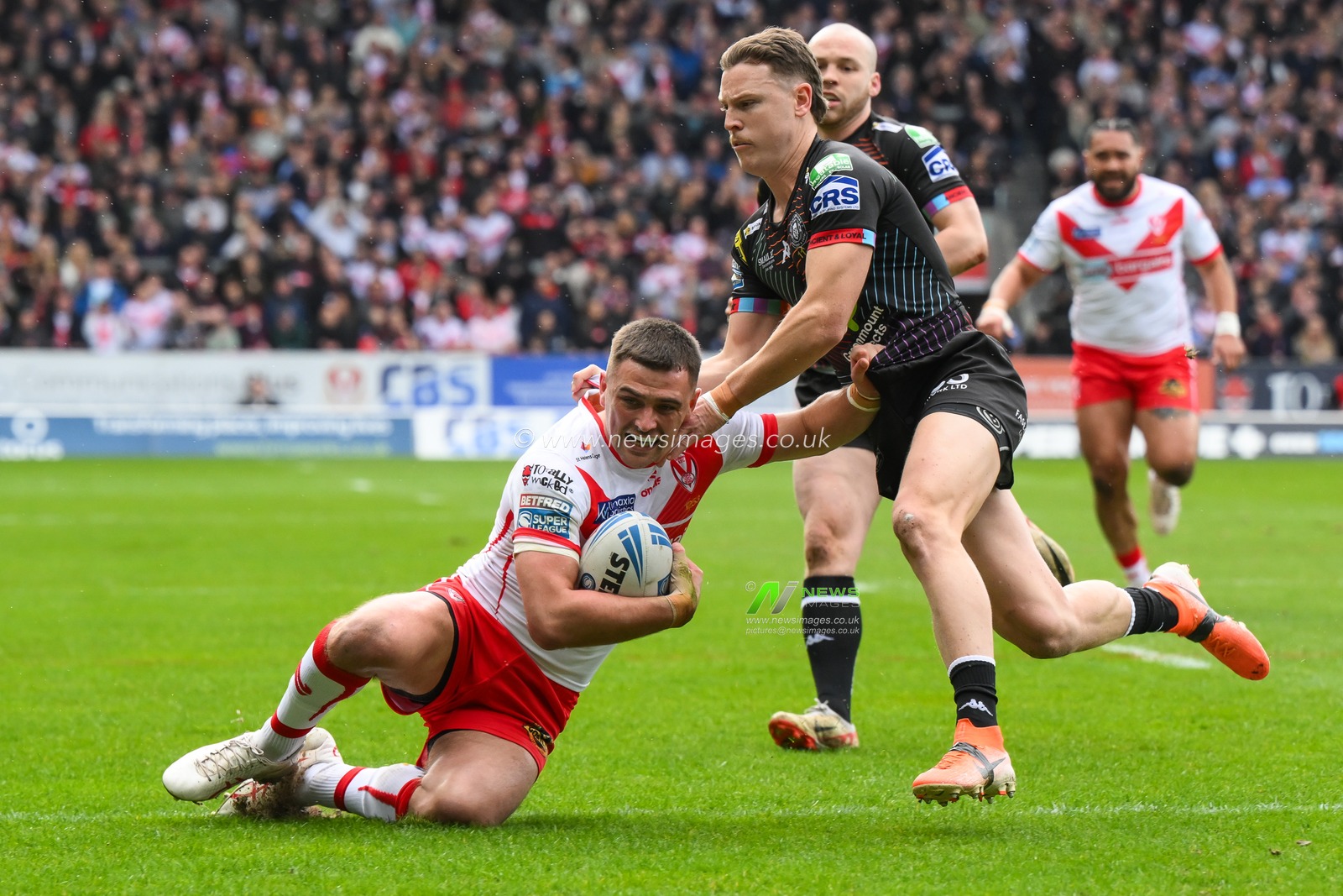 Lewis Dodd of St. Helens is tackled by Jai Field of Wigan Warriors  during the Betfred Super League Round 6 match St Helens vs Wigan Warriors at Totally Wicked Stadium, St Helens, United Kingdom, 29th March 2024

(Photo by Craig Thomas/News Images)
