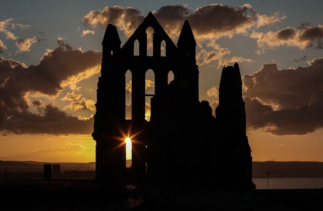 The sun sets behind Whitby Abbey