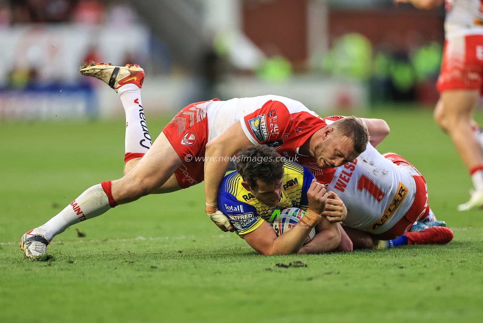 Stefan Ratchford #1 of Warrington Wolves is tackled by Jack Welsby #1 of St Helens and Joe Batchelor #12 of St Helens