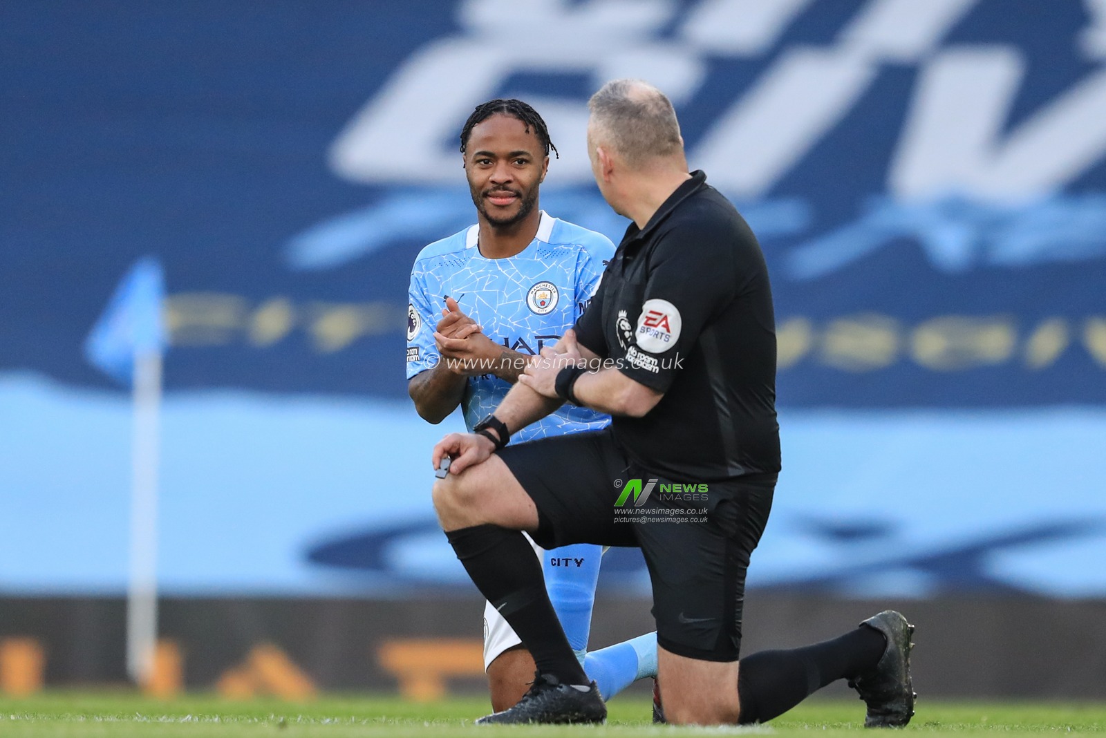 Raheem Sterling #7 of Manchester City and referee Jonathan Moss take the knee