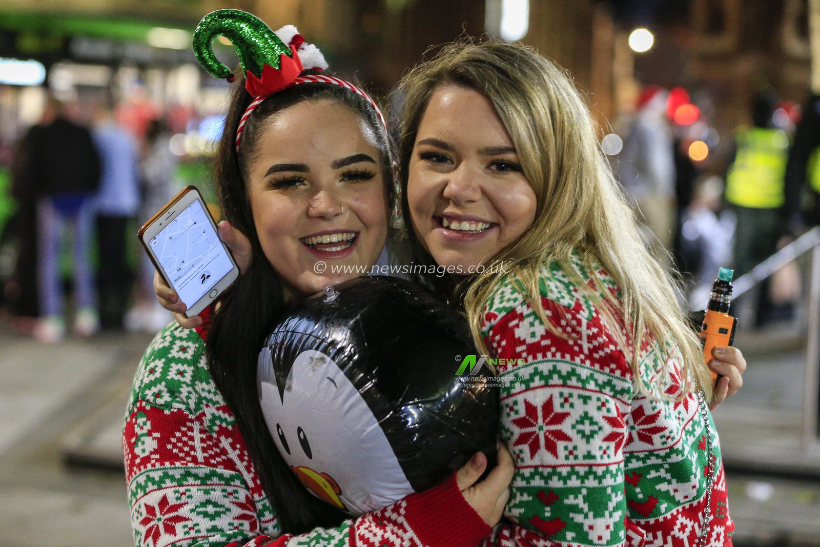 Two friends in Christmas jumpers looking happy after a night out in the Bigg Market, Newcastle upon Tyne, on the eve of the second national lockdown
