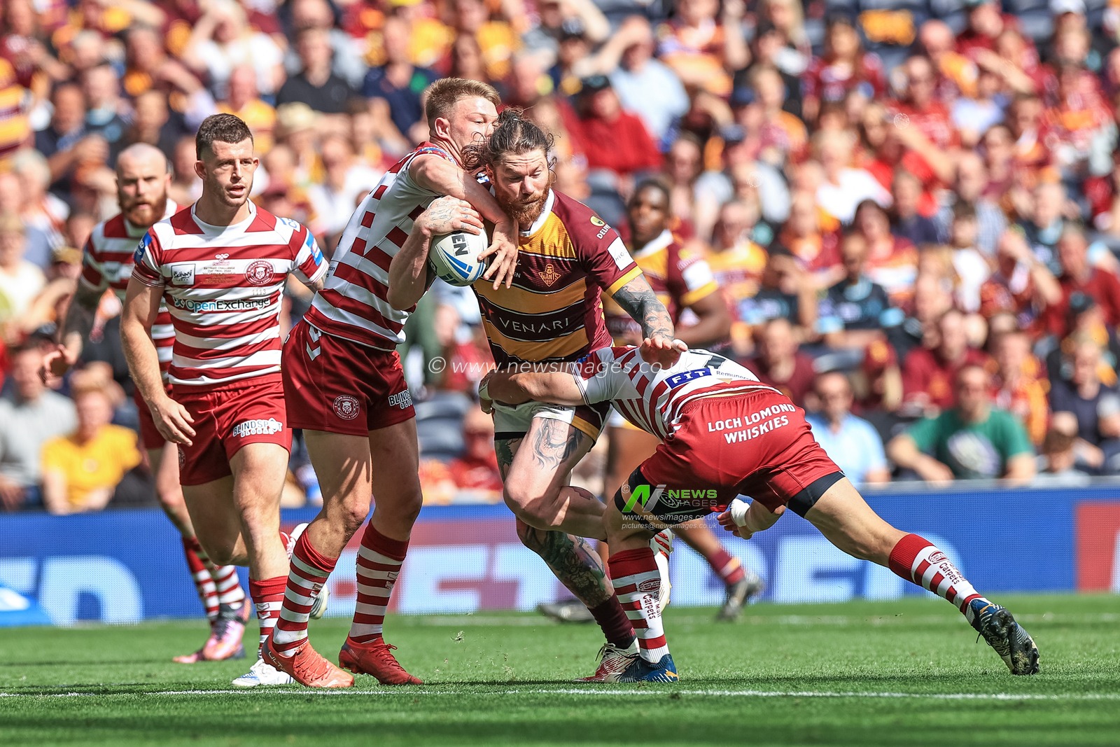 Chris McQueen #12 of Huddersfield Giants is tackled by Morgan Smithies #14 of Wigan Warriors and Thomas Leuluai #7 of Wigan Warriors