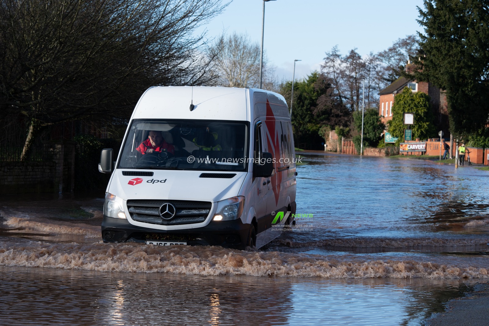 A DPD driver navigates his way through the deep flood water to his next delivery