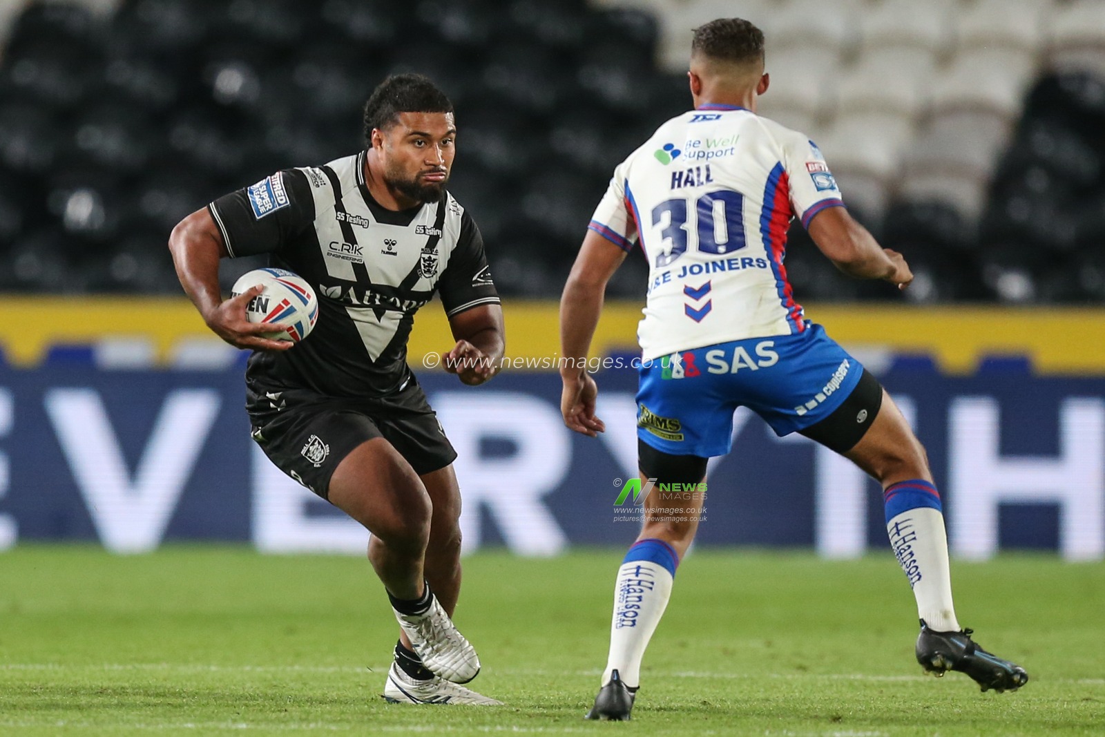 Chris Satae #10 of Hull FC runs at Corey hall #30 of Wakefield Trinity