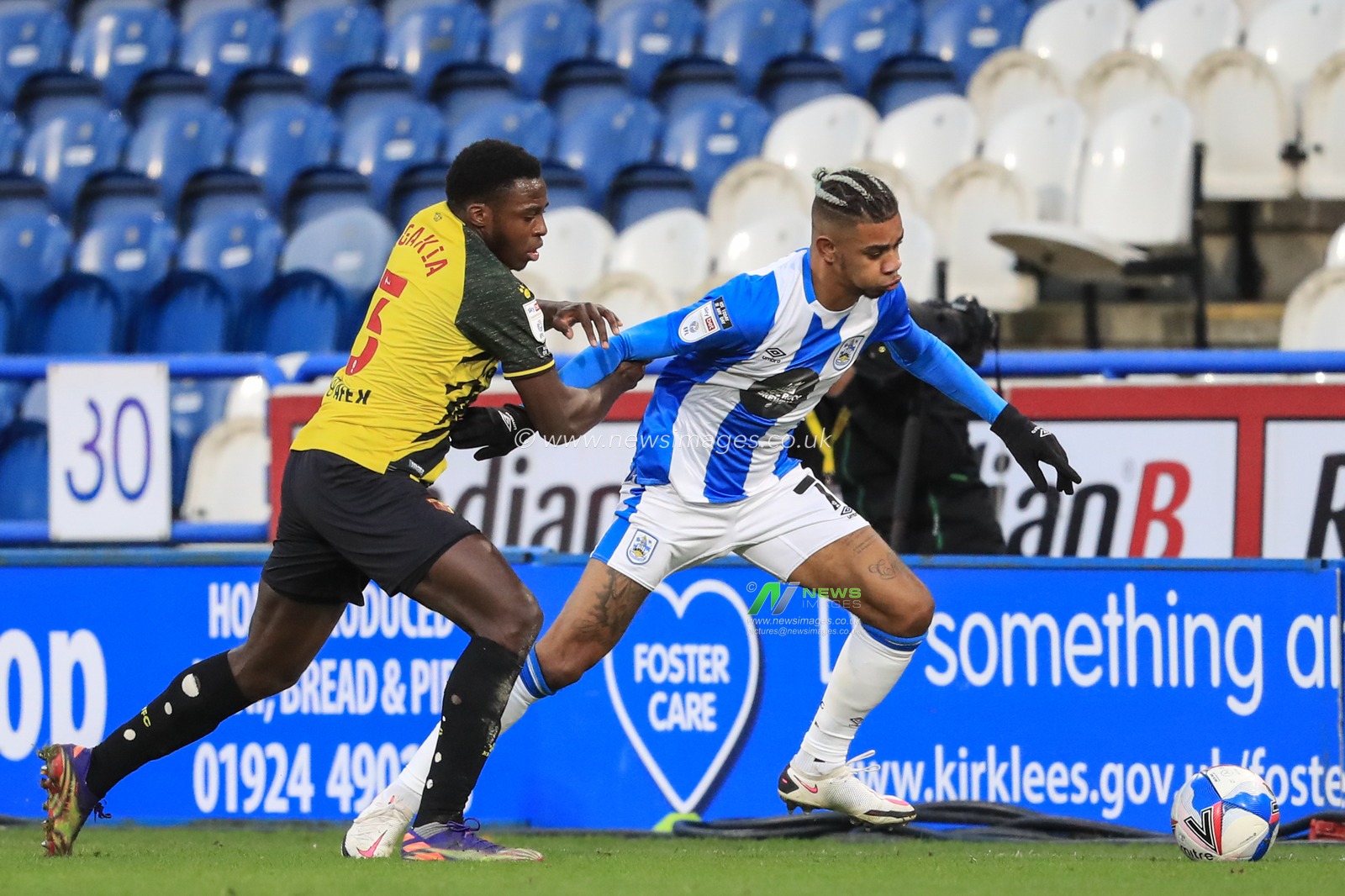 Juninho Bacuna #7 of Huddersfield Town holds off Jeremy Ngakia #3 of Watford