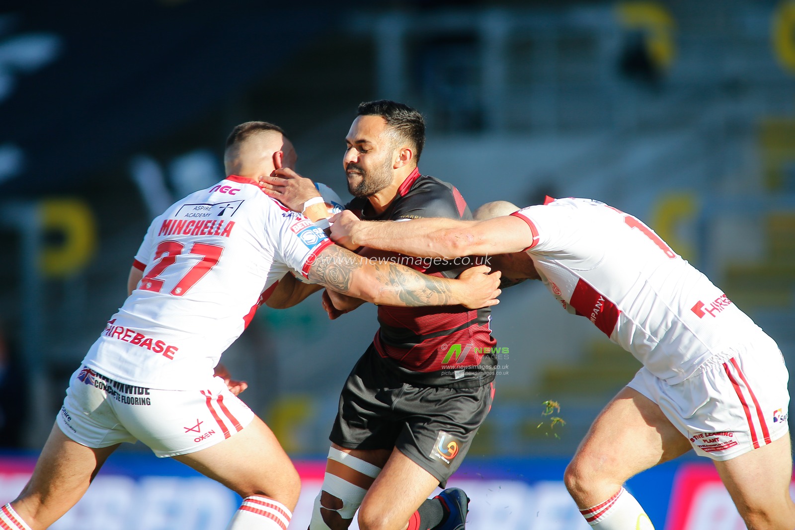 Bevan French (6) of Wigan Warriors tackled by Elliot Minchella (27) and Dean Hadley (13) of Hull KR.
