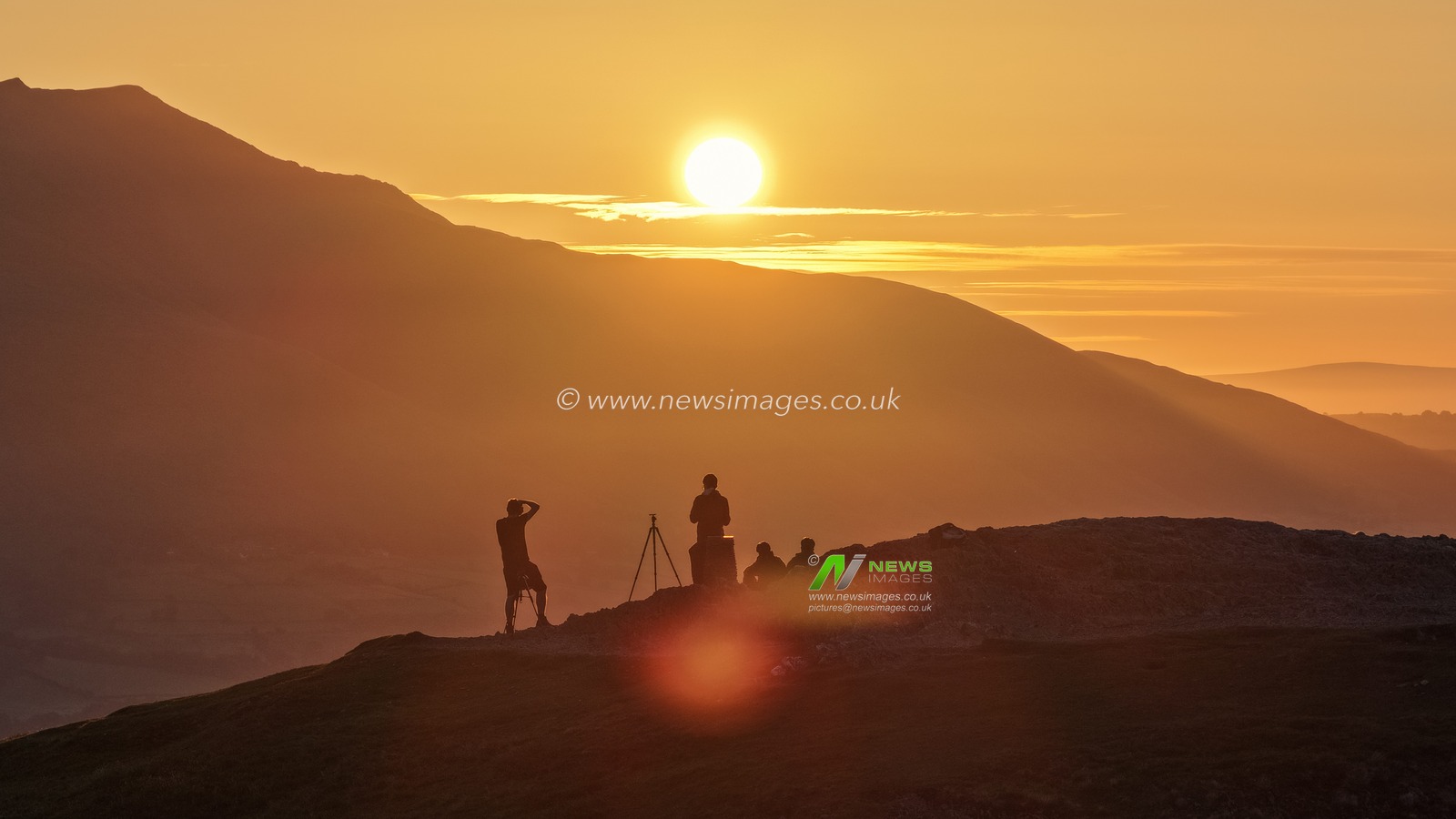 Photographers take pictures as the sun rises from the summit of Catbells overlooking Derwent Water and the town of Keswick In the Lake District, Cumbria, United Kingdom, 19th June 2025

(Photo by Mark Cosgrove/News Images)