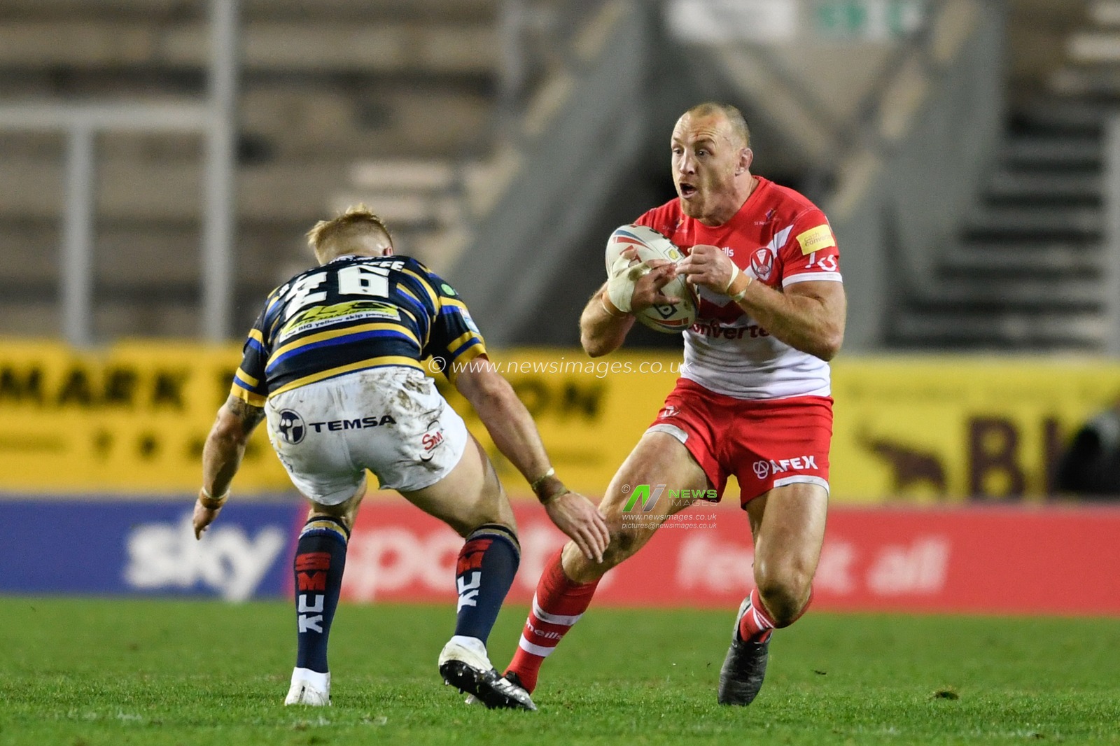 James Roby (9) of St Helens looks for a way past Alex Sutcliffe (26) of Leeds Rhinos
