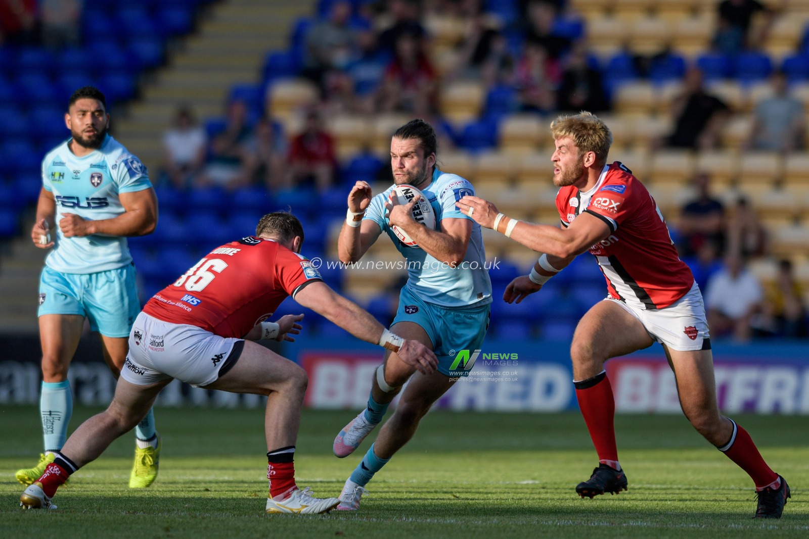 Liam Kay (5) of Wakefield Trinity looks for a way past Greg Burke (16) of Salford Red Devils and Jack Ormondroyd (25) of Salford Red Devils