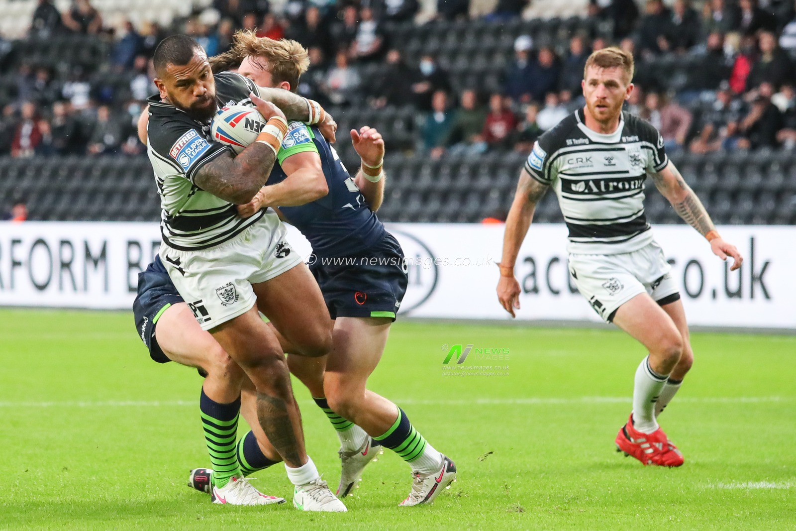 Manu Ma'u (12) of Hull FC is tackled by the Huddersfield defence